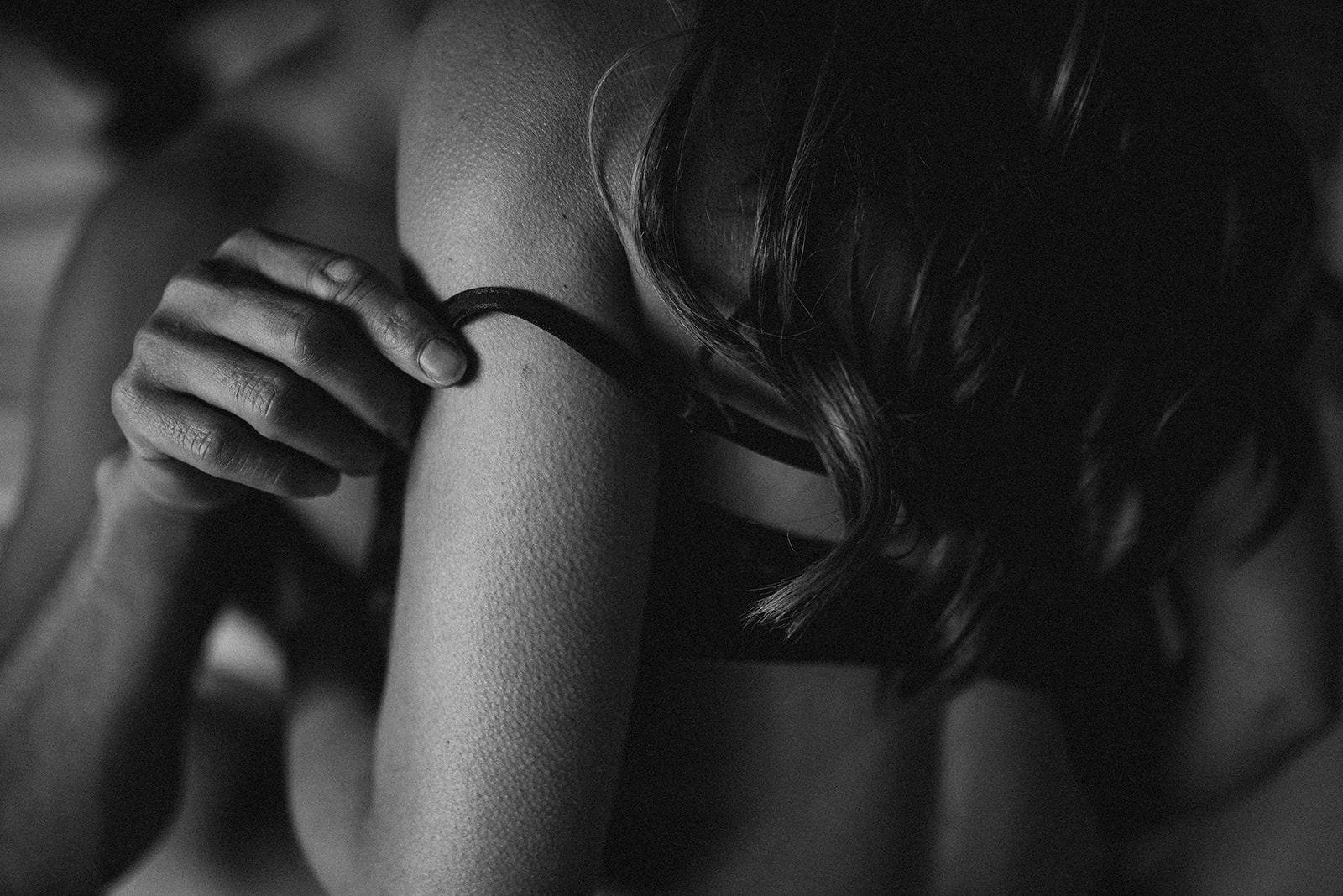 detail shot of a man peeling down his partner's bra strap during their boudoir photoshoot