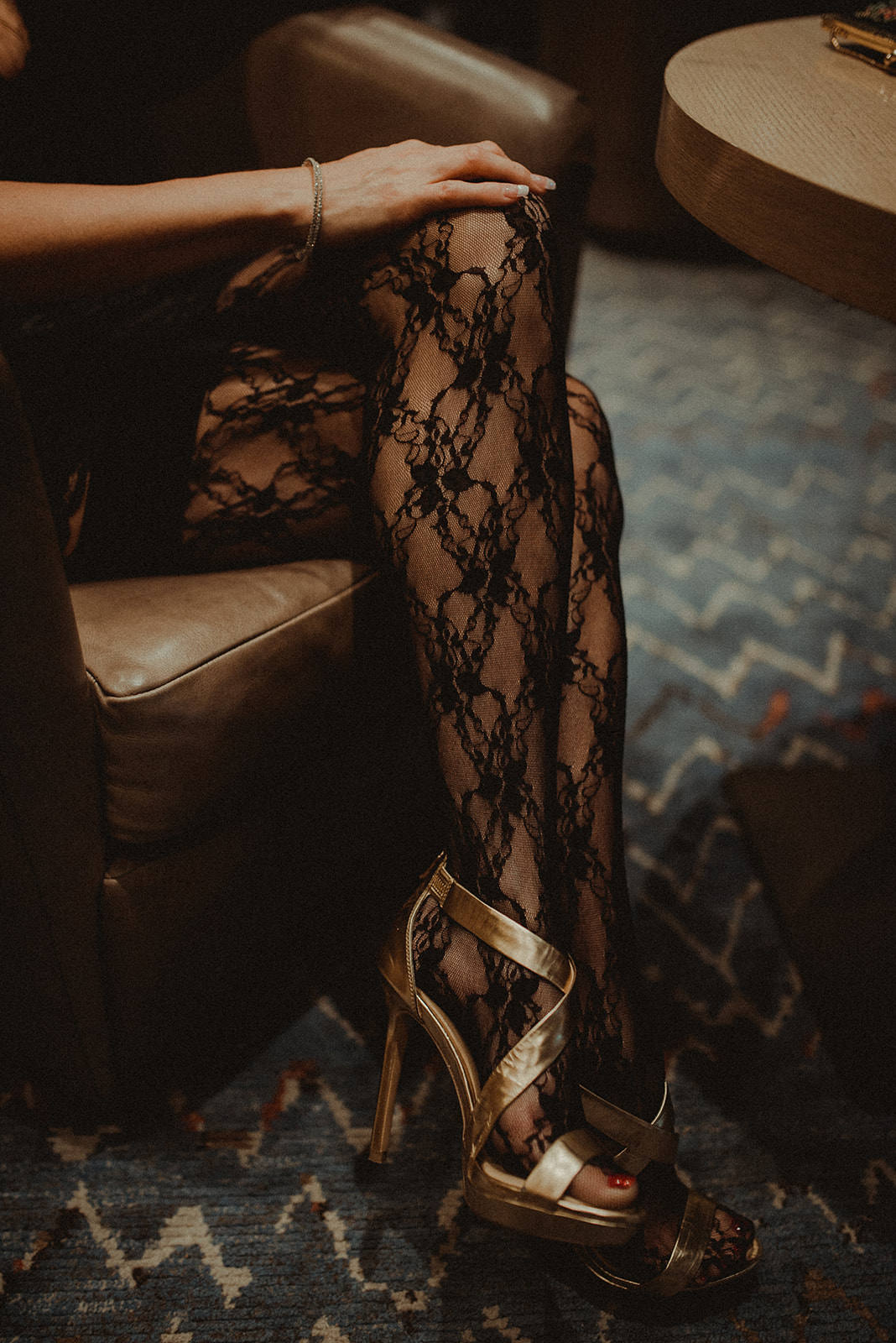 detail shot of a woman's gorgeous lace leggings and heels as she waits for her partner to arrive in a hotel lobby