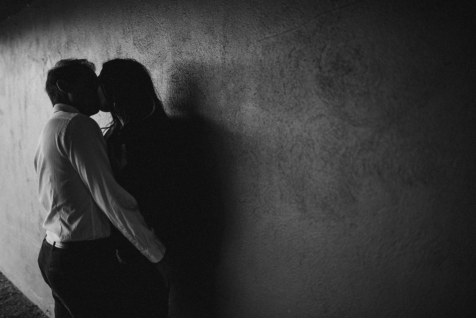 black and white photo of a couple kissing in a dark hallway during their couple's boudoir photoshoot