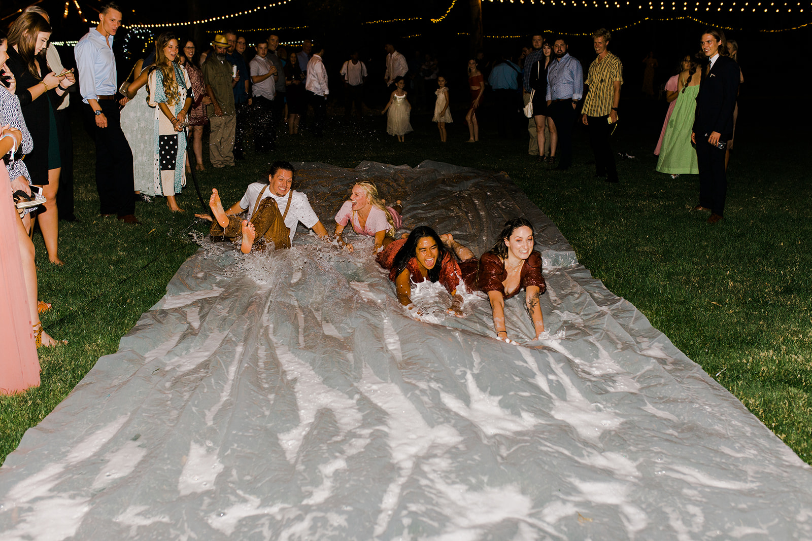boho- chic couple does a slip 'n slide wedding exit followed by the bridal party and guests