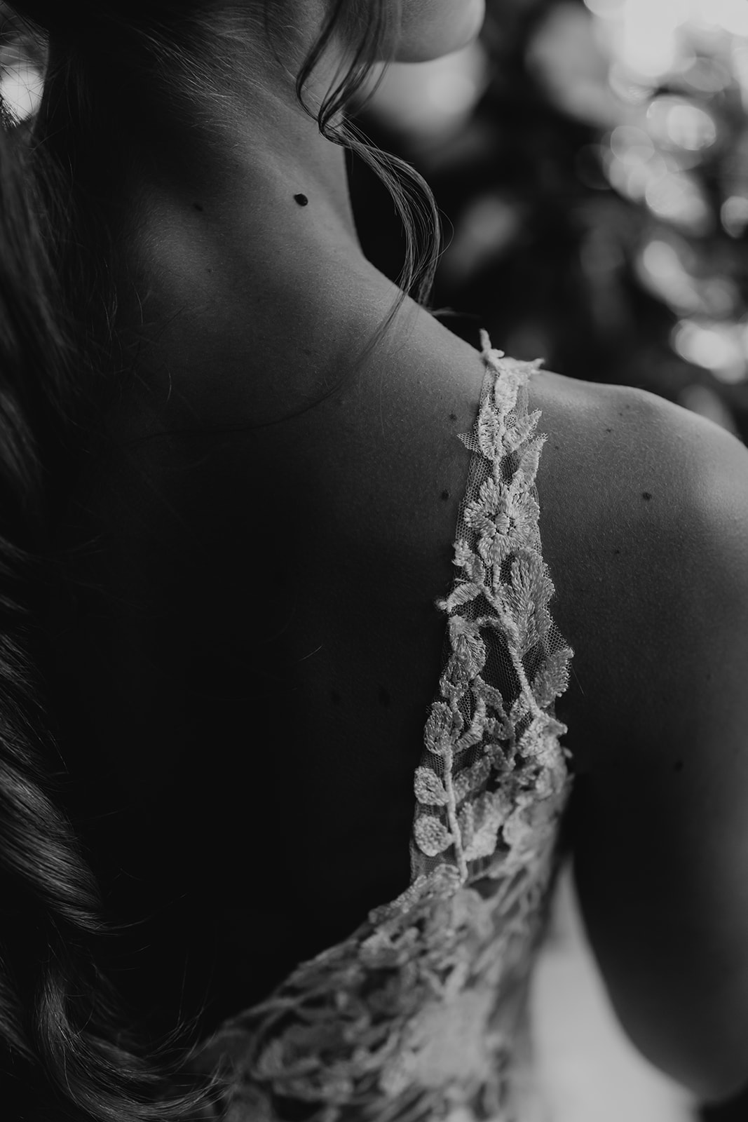 Black and white image with a close up of a lace strap sleeve on a wedding dress. 