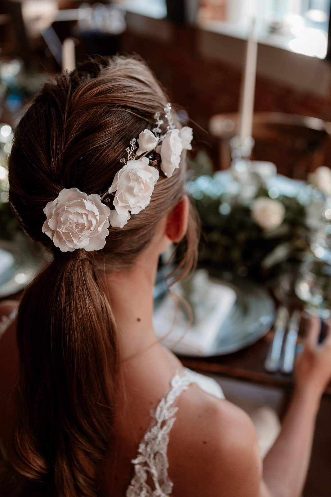 Close up of white rose hair accessories on a bridal ponytail. 