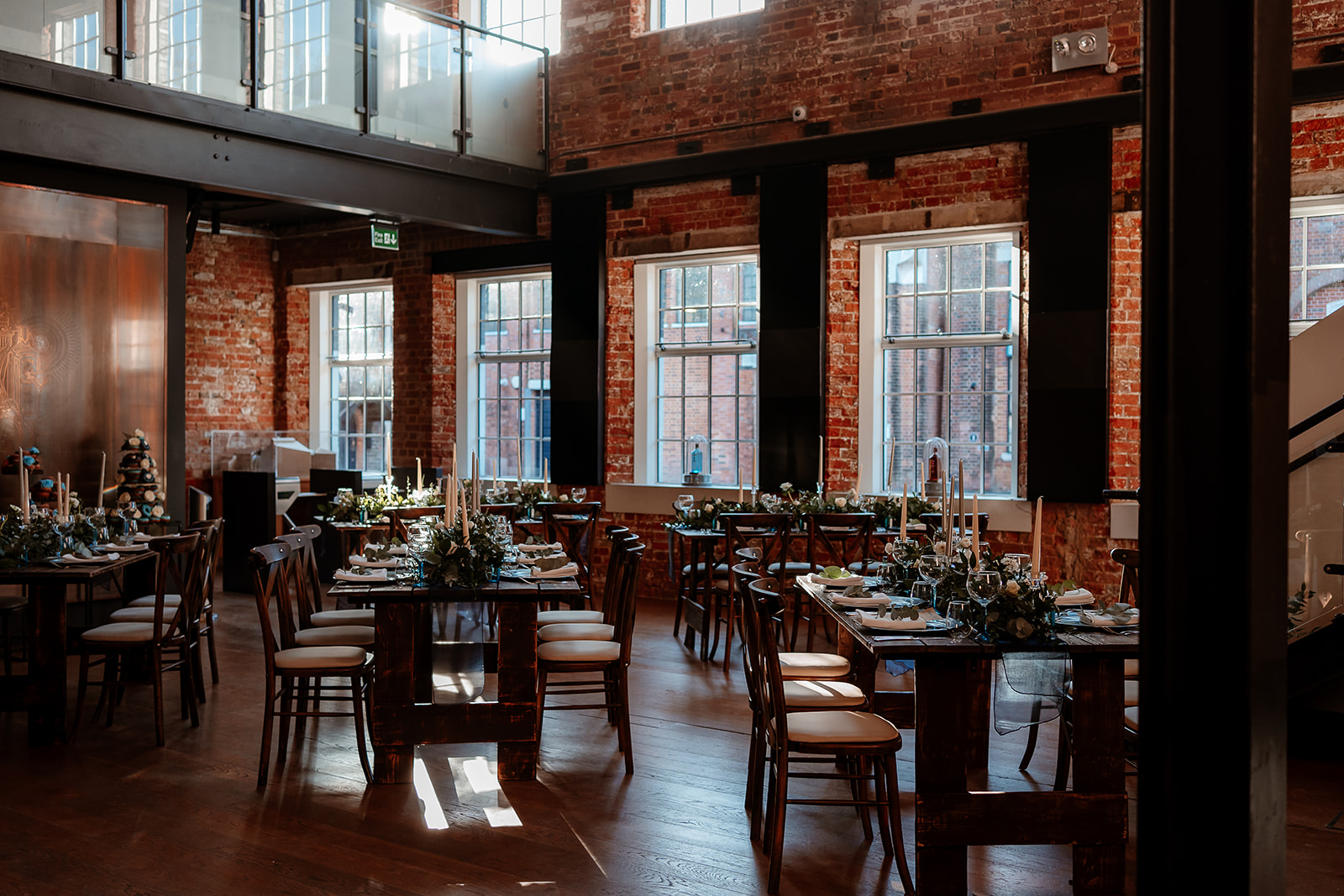 Wedding breakfast tables with green and white flower table runners and tapered candles at the Bombay Sapphire Distillery