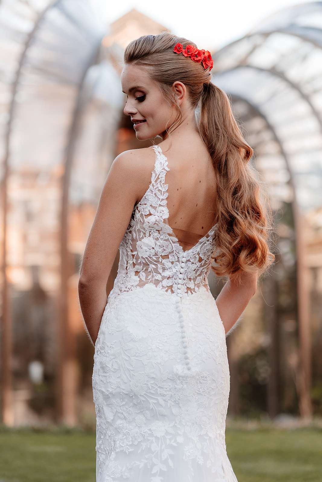 Bride in a white lace dress stands in front of the Bombay Sapphire Distillery Glasshouses. 