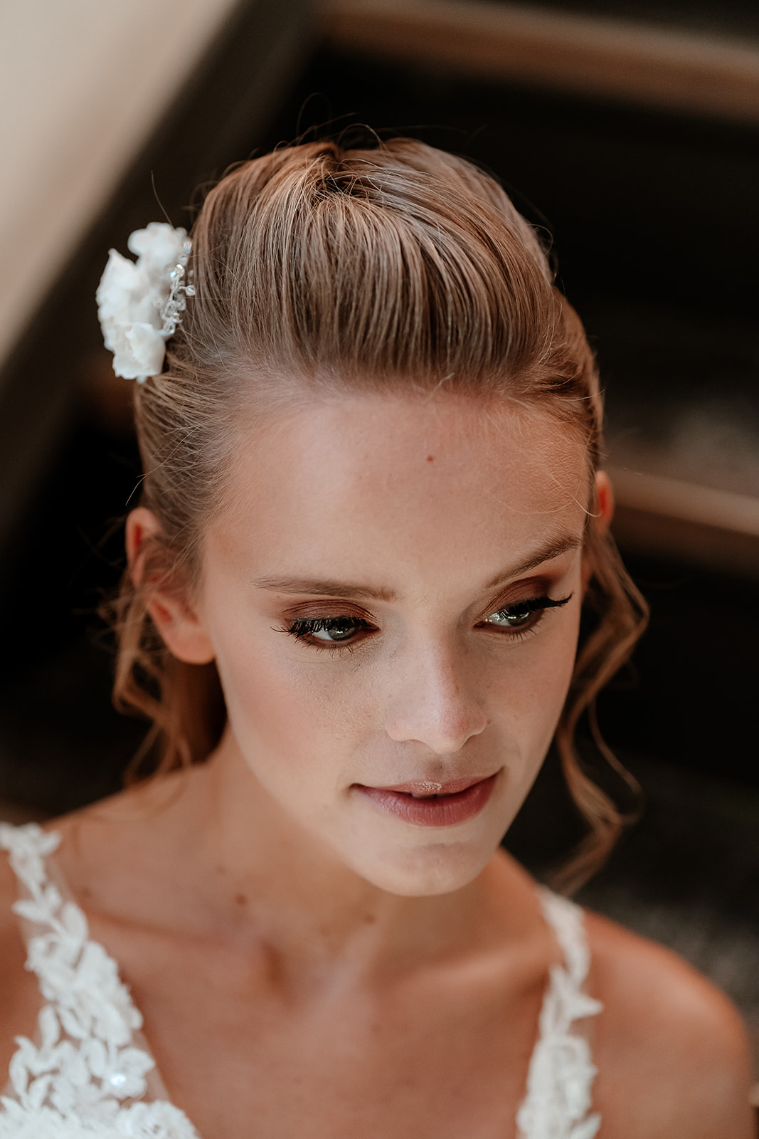 Close up on the face of a bride with soft make up, her hair in a ponytail with soft curls framing her face. 