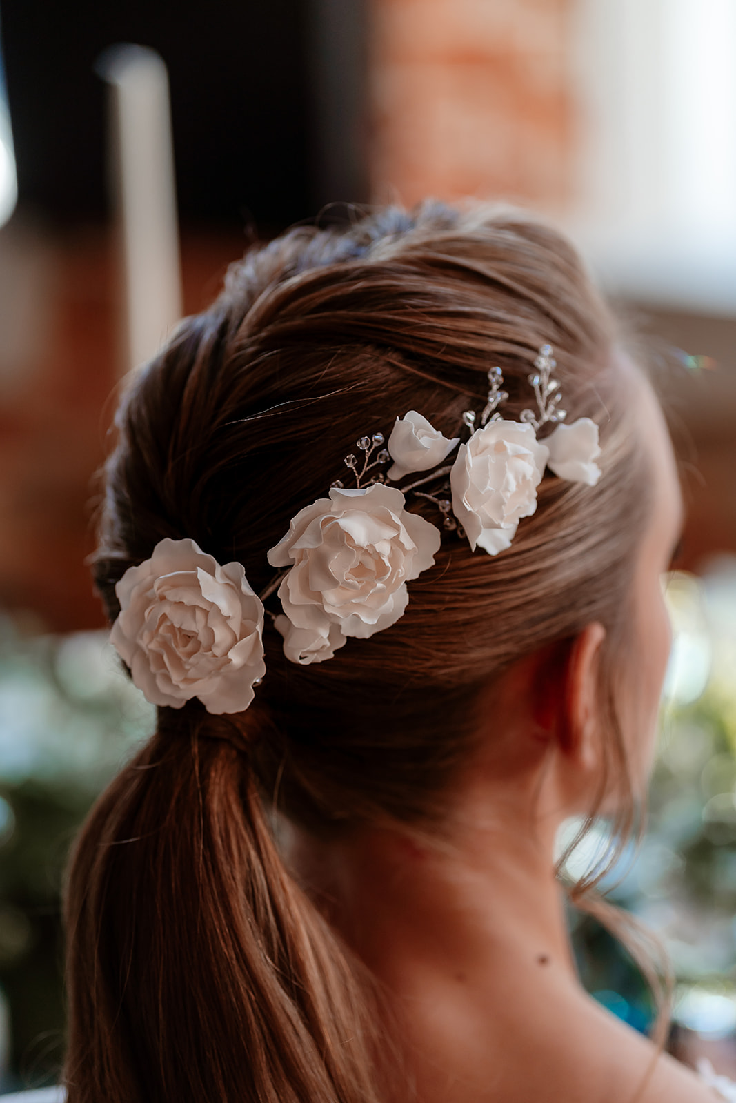 Close up of white rose hair accessories on a bridal ponytail. 