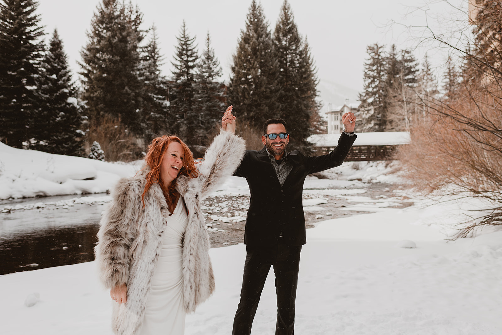 Couple celebrates after getting married in a snowy landscape with a river behind them in Vail Colorado 
