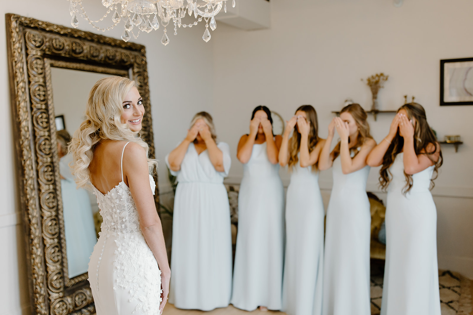 Bride looks over her shoulder as her bridesmaids await their first look with her. 