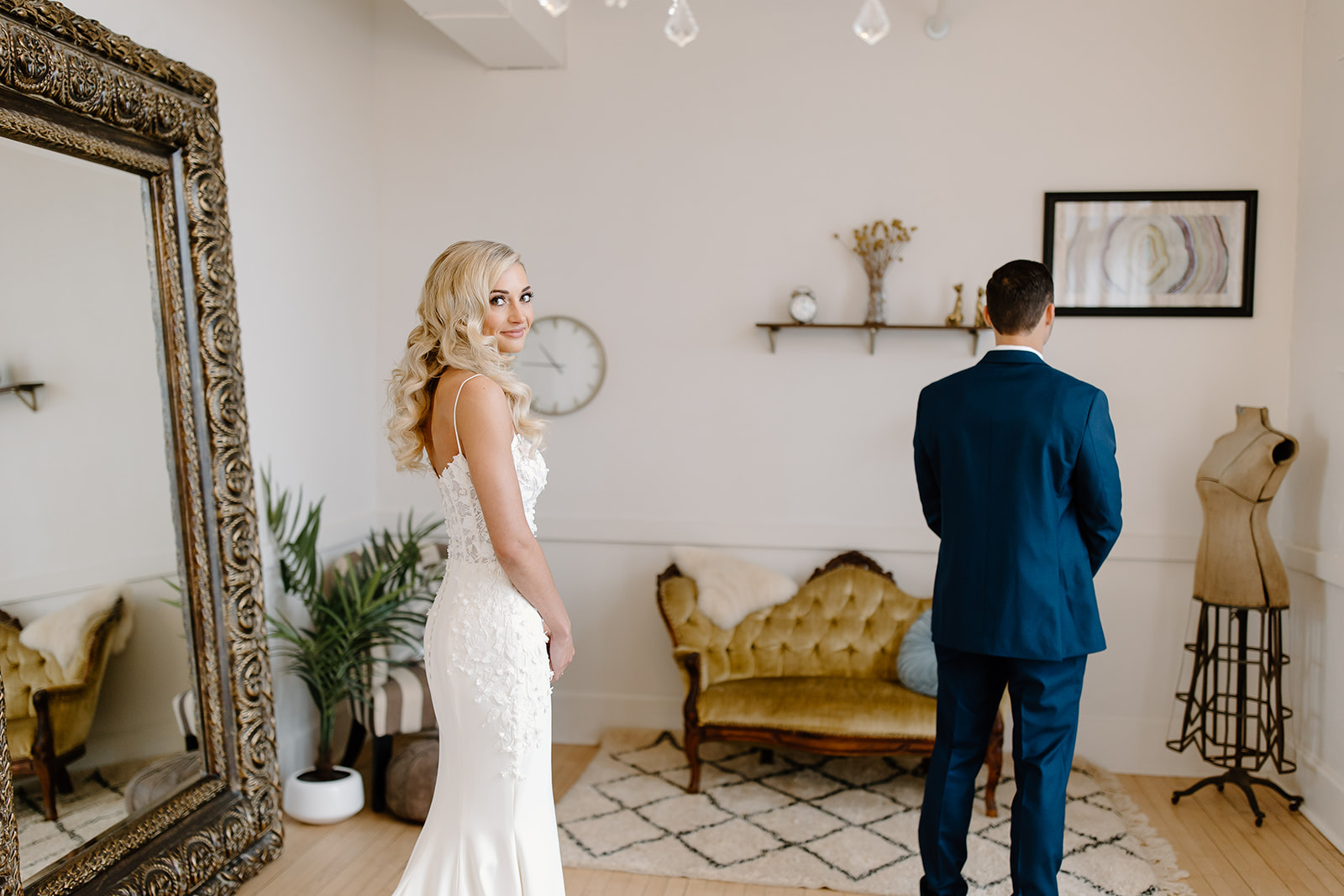 Bride looks over her shoulder at the camera while her groom is waiting to see her for the first time.