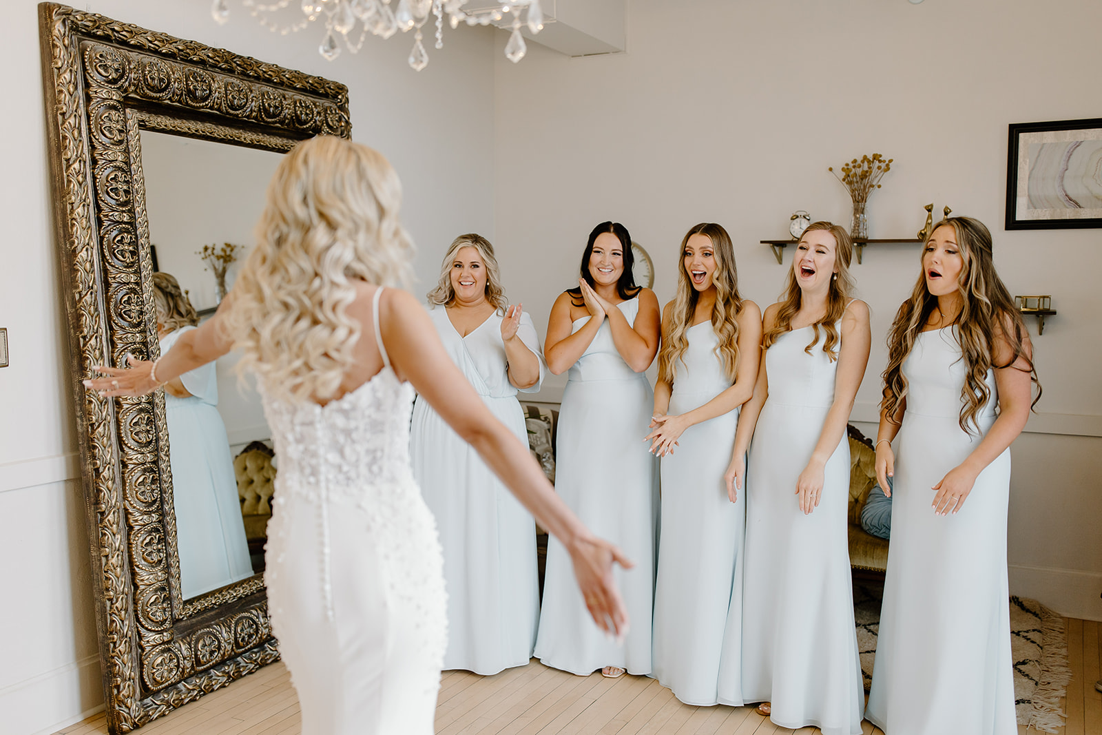 Bride poses for her bridesmaids as they see her final look for the first time.