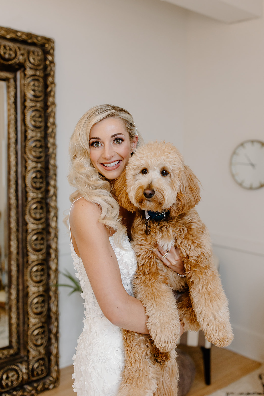 Bride poses in her wedding dress while holding her dog.