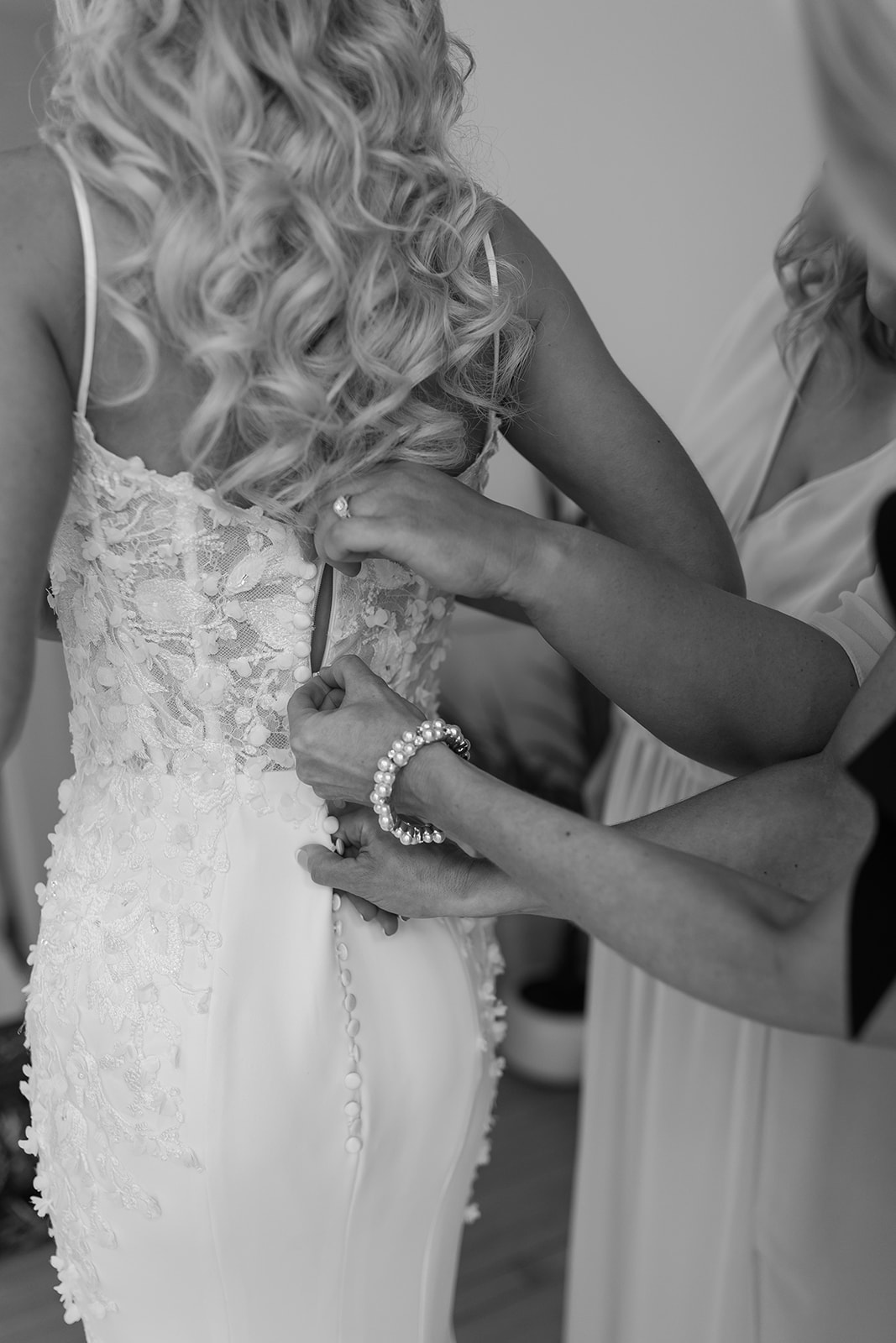 Bride's mom and sister zip up her wedding dress the morning of her wedding day.