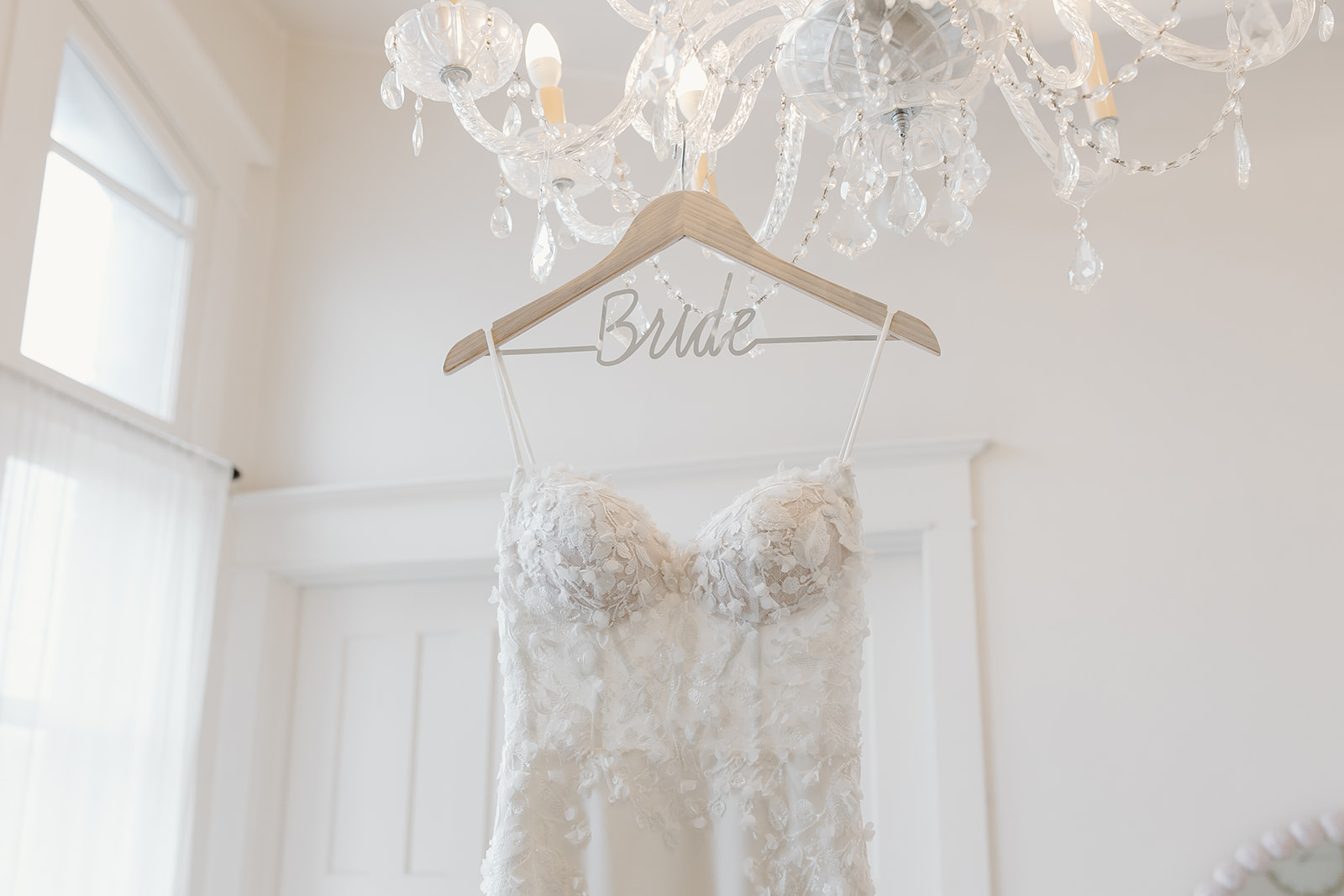 A close up of the bodice of the bride's wedding dress. The hanger says bride in cursive. 