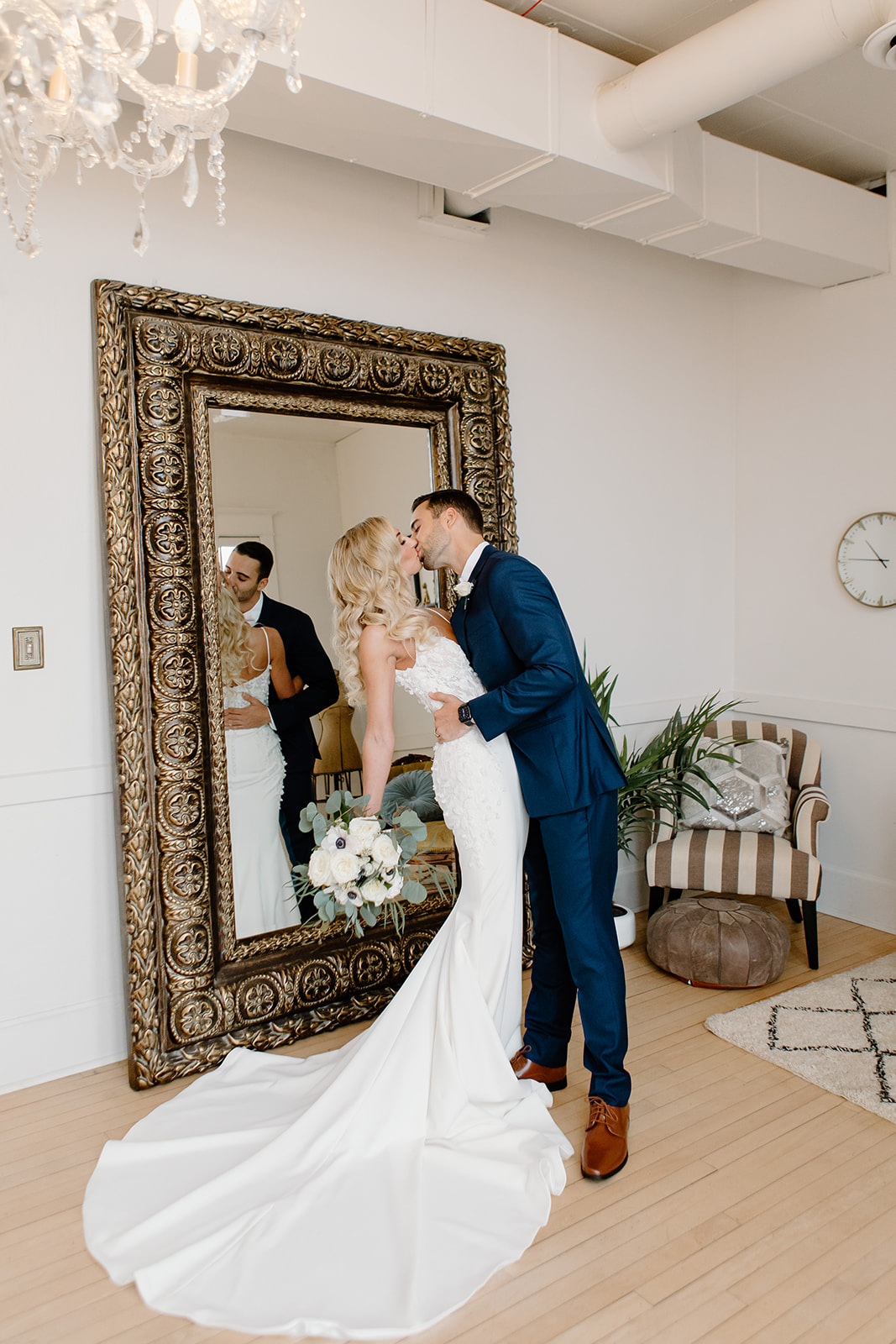 Groom dips his bride backwards in front of a large mirror.