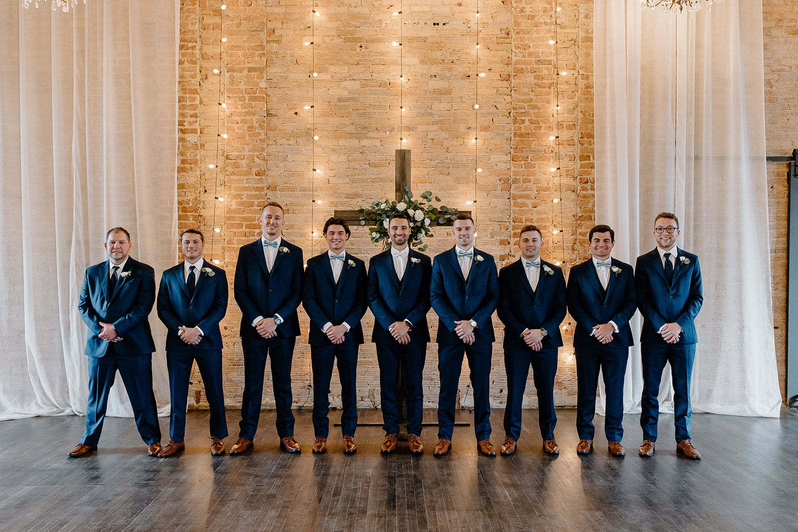 Groom and his groomsmen pose in front of a cross. 