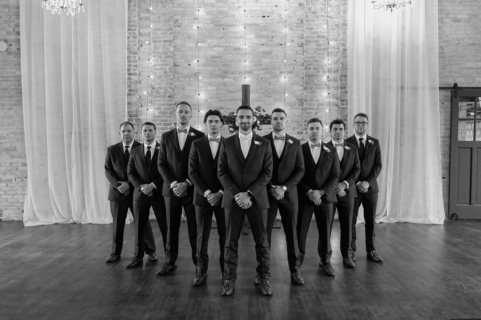 Groom and his groomsmen pose in front of a cross. 