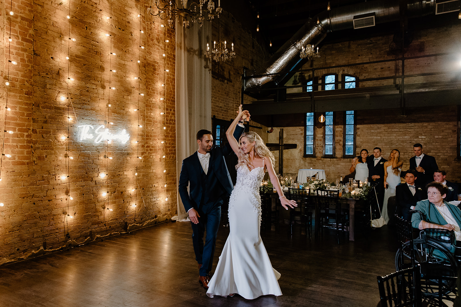 Groom twirls his bride on the dance floor at their wedding venue.