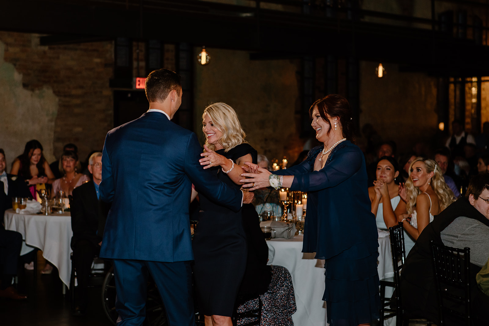 Mother of the groom encourages mother of the bride to dance with her son as well.
