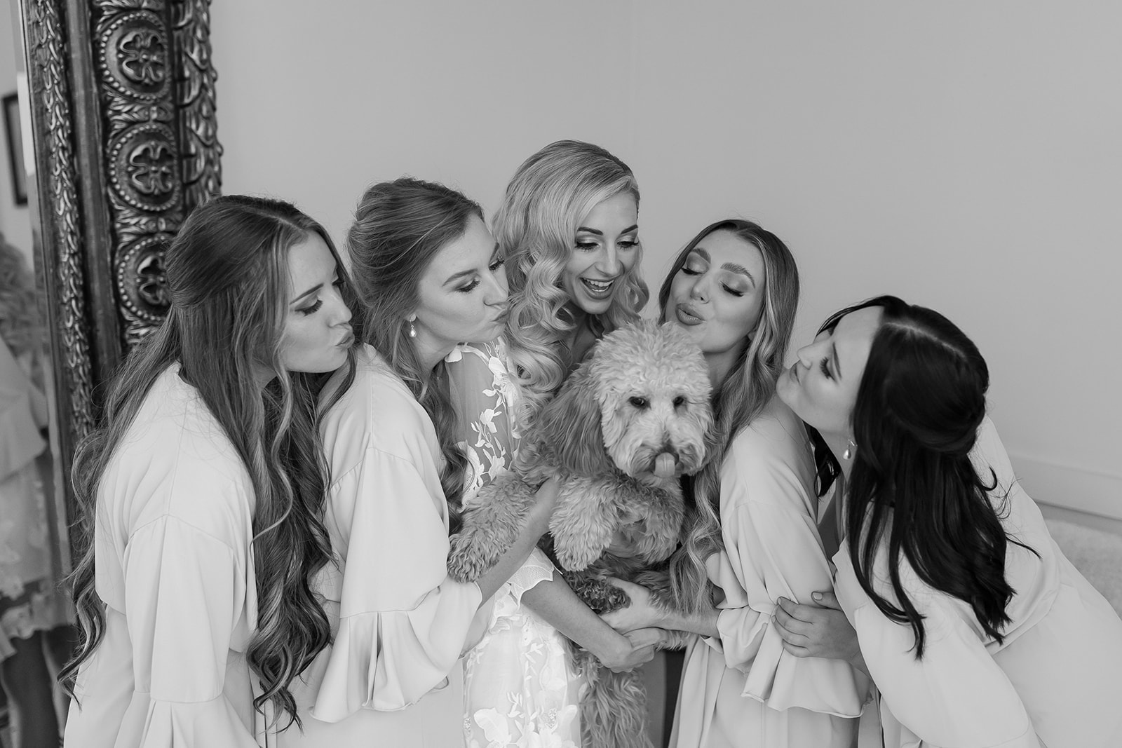 The bride and her bridesmaids love on her puppy.