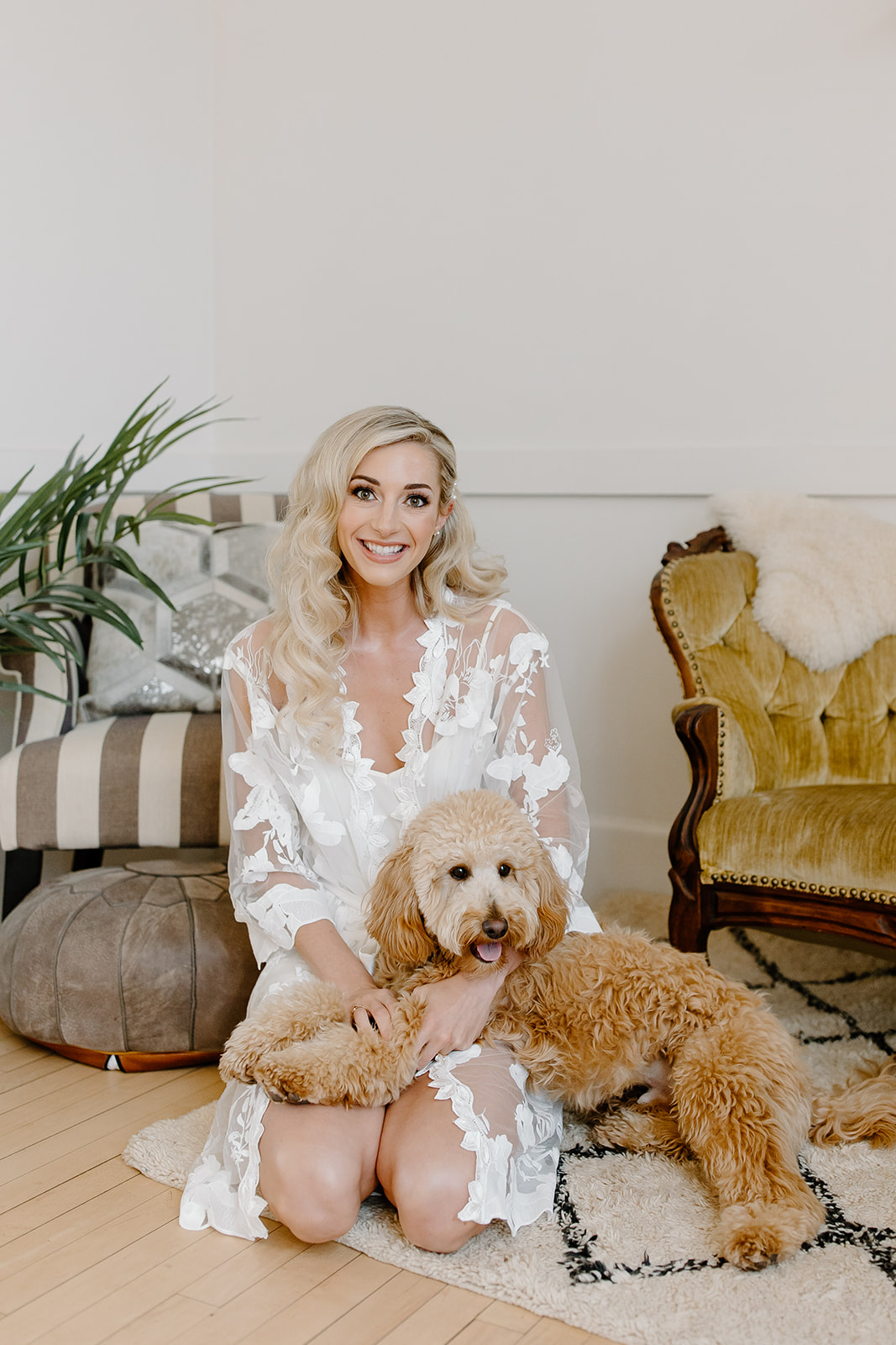 The bride poses in her getting ready outfit with her mini golden doodle. 