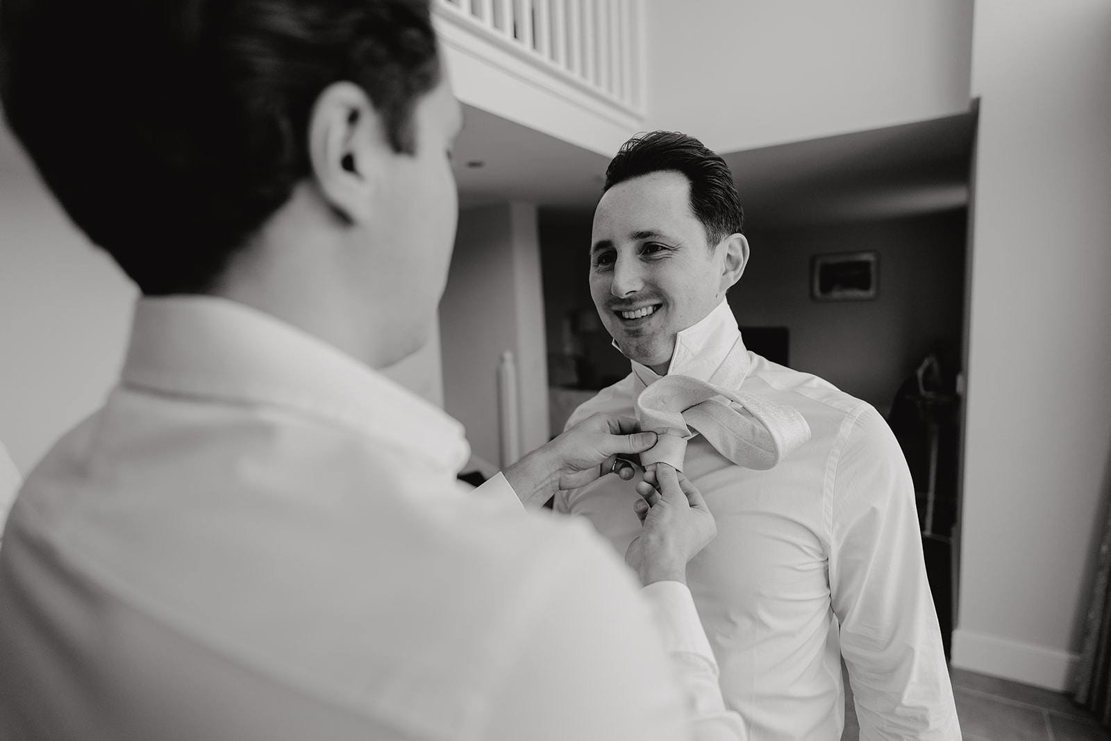 The groom, having a hand with his tie on the morning of his wedding