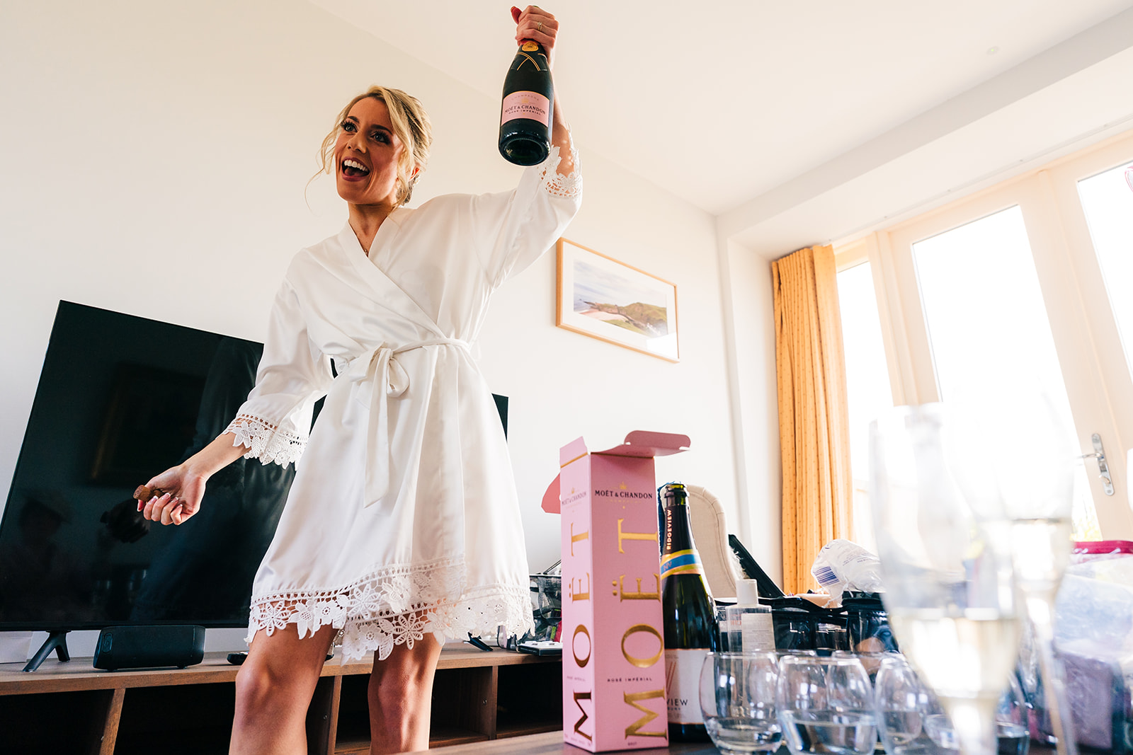 The bride popping the champagne bottle on the morning of her wedding