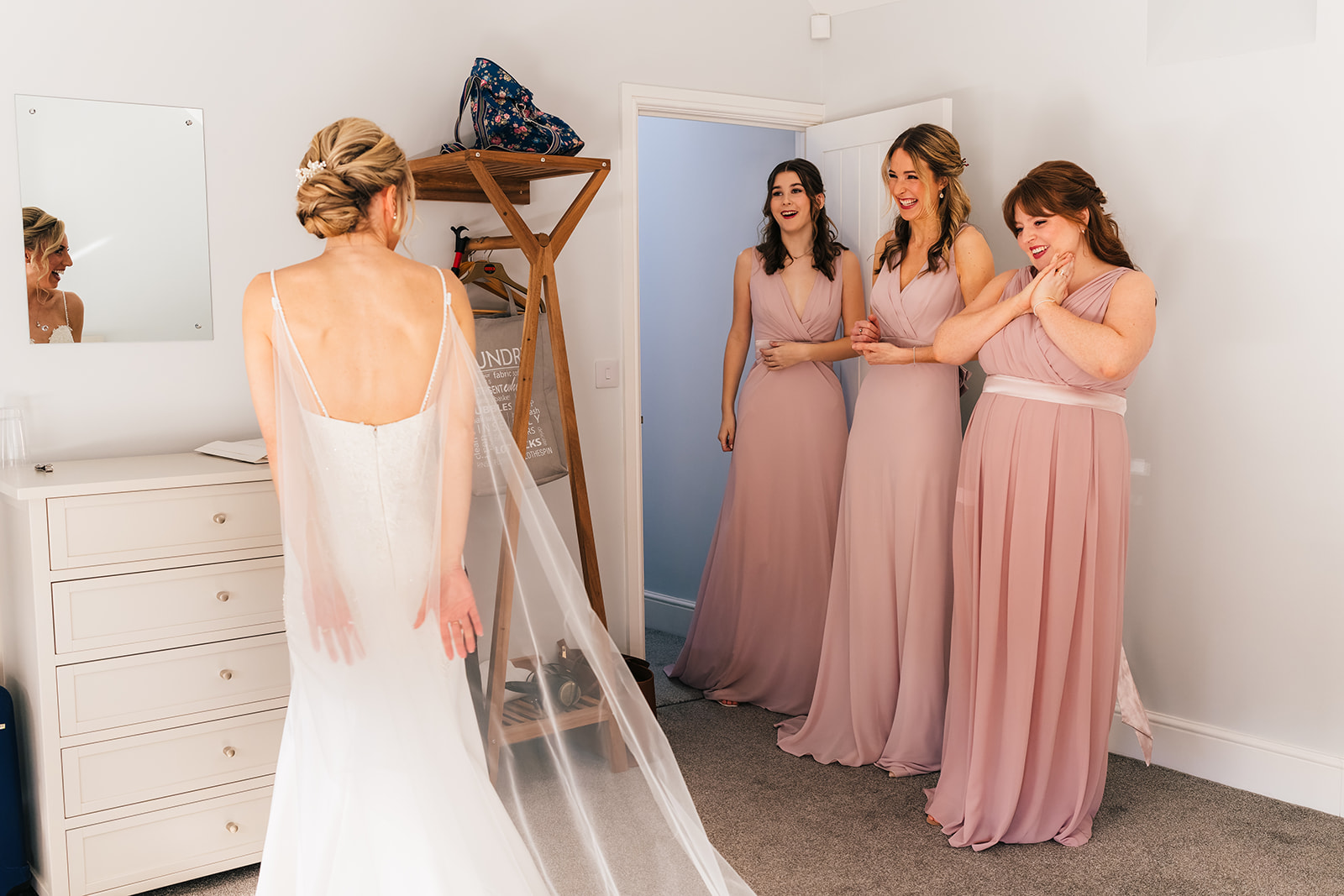 The bridesmaids reacting to seeing their friend in her wedding dress