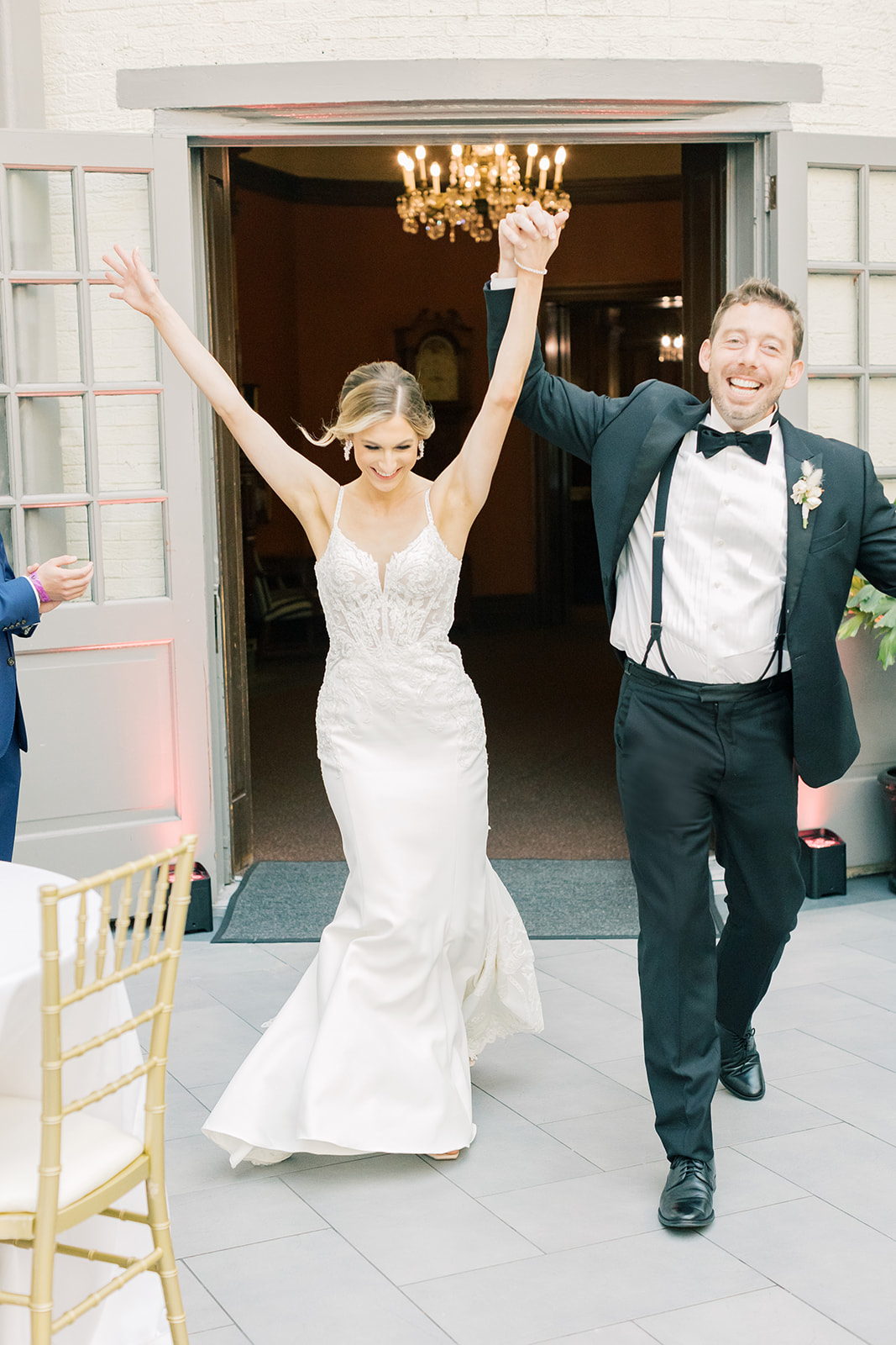 Bride and groom walk into their reception hands in the air. 