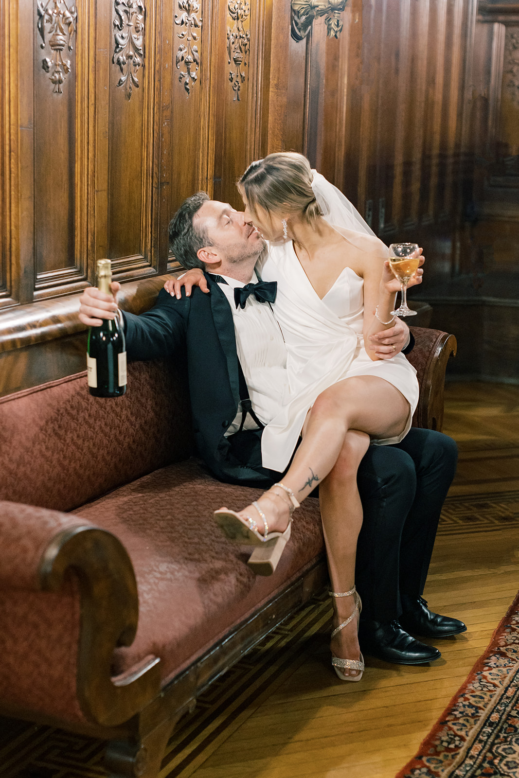 Bride and groom kiss with champagne glasses in hand. 