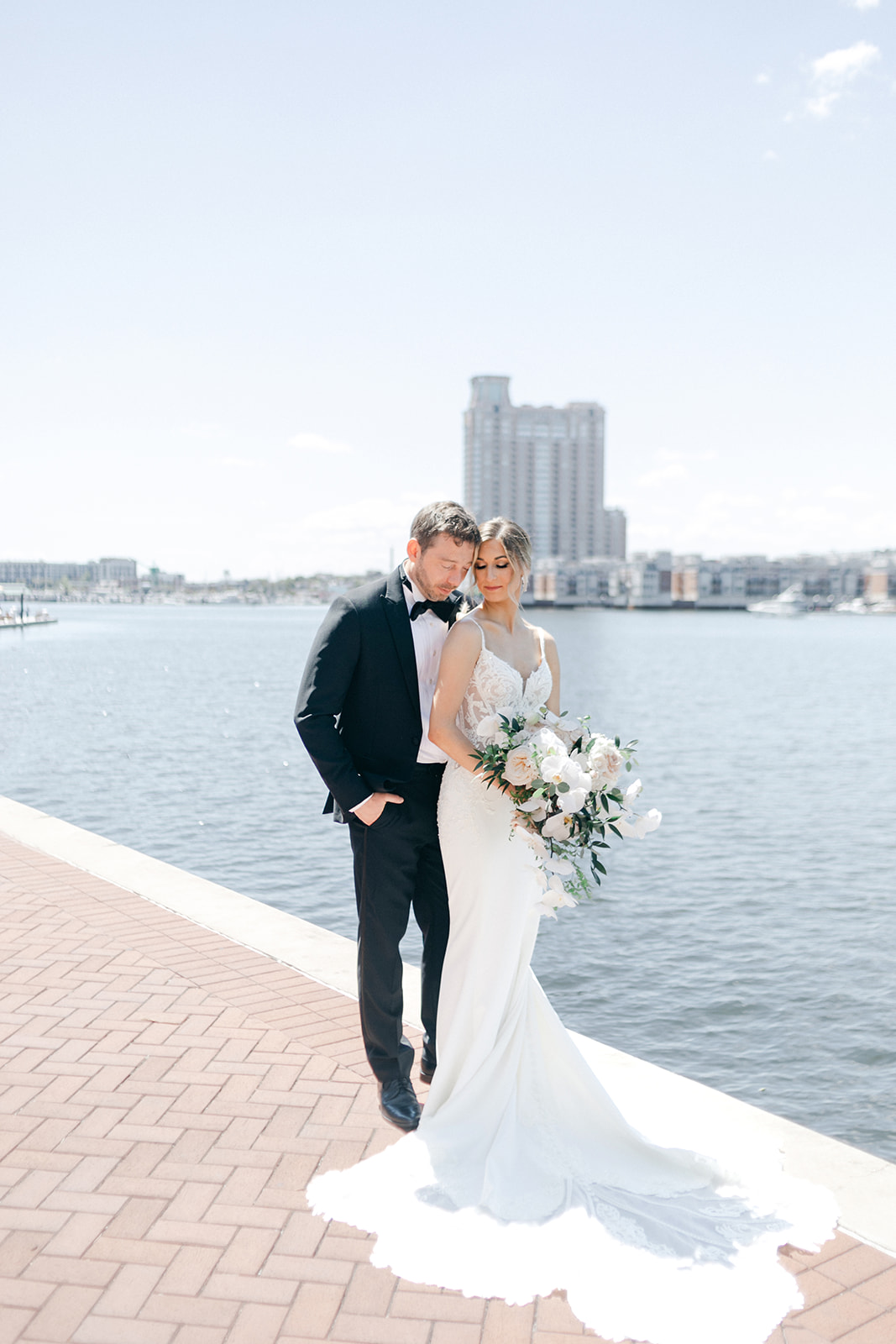 Bride and groom pose in front of the Baltimore Harbor. 