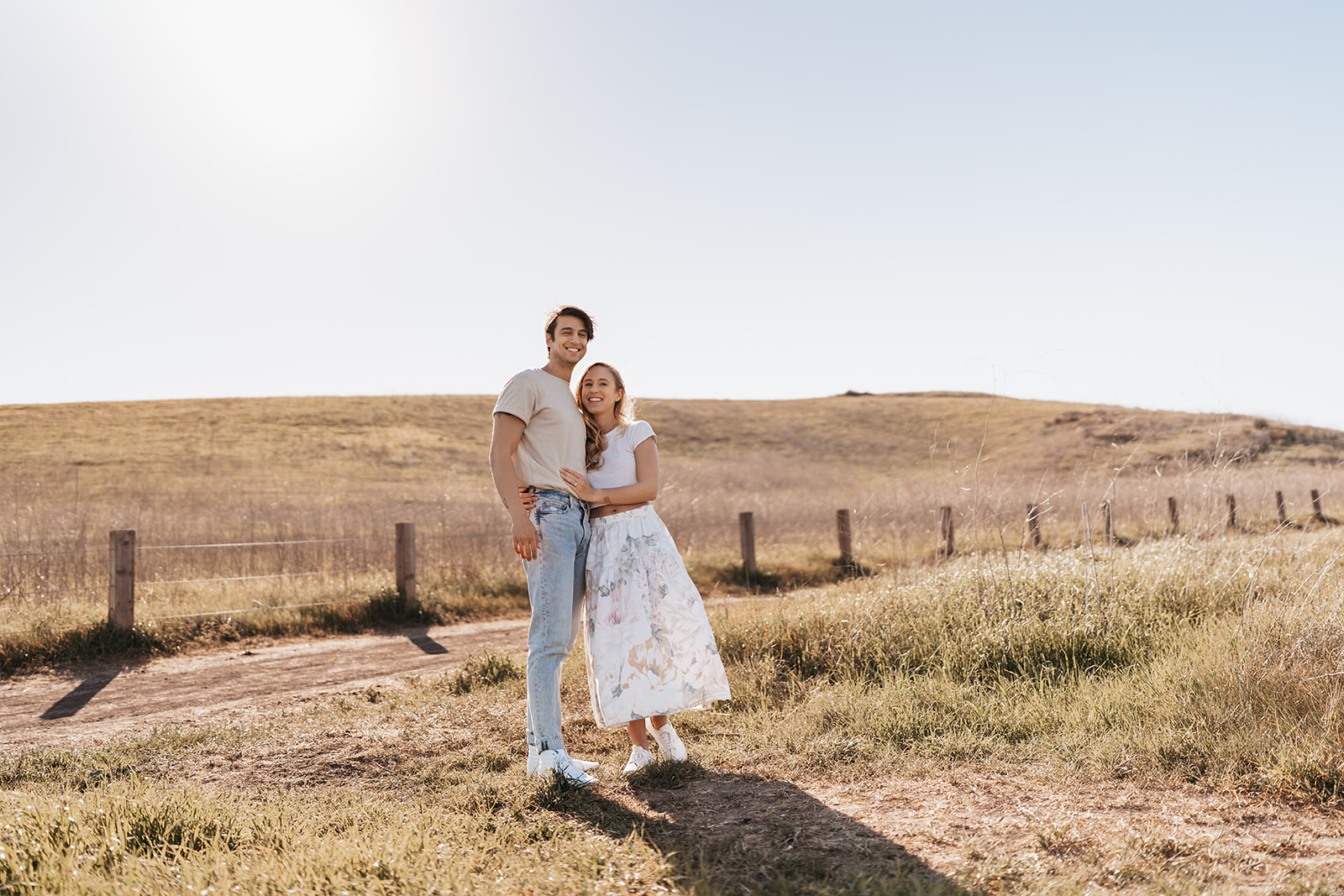 a couple takes engagement photos at sunset on a grassy hill in irvine california