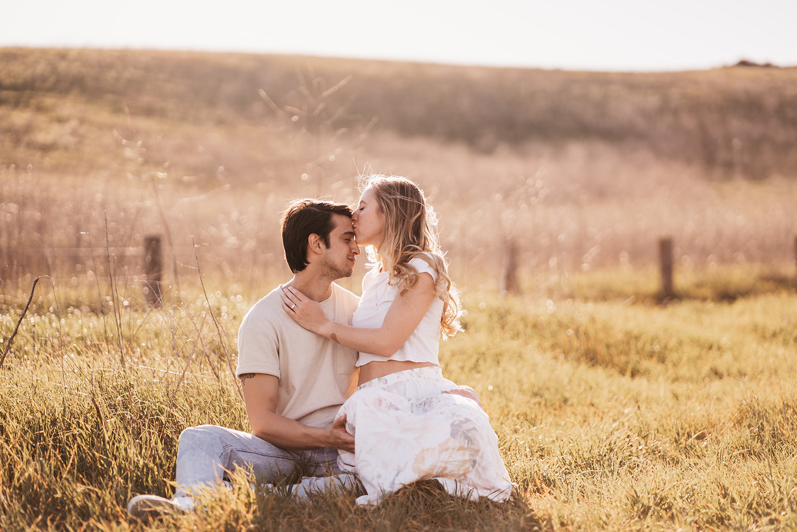 a couple takes engagement photos at sunset on a grassy hill in irvine california