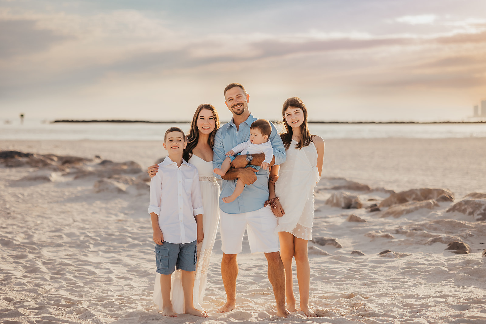 Beach Family Photoshoot in Orange Beach - Family group photo with water and rocks in the background