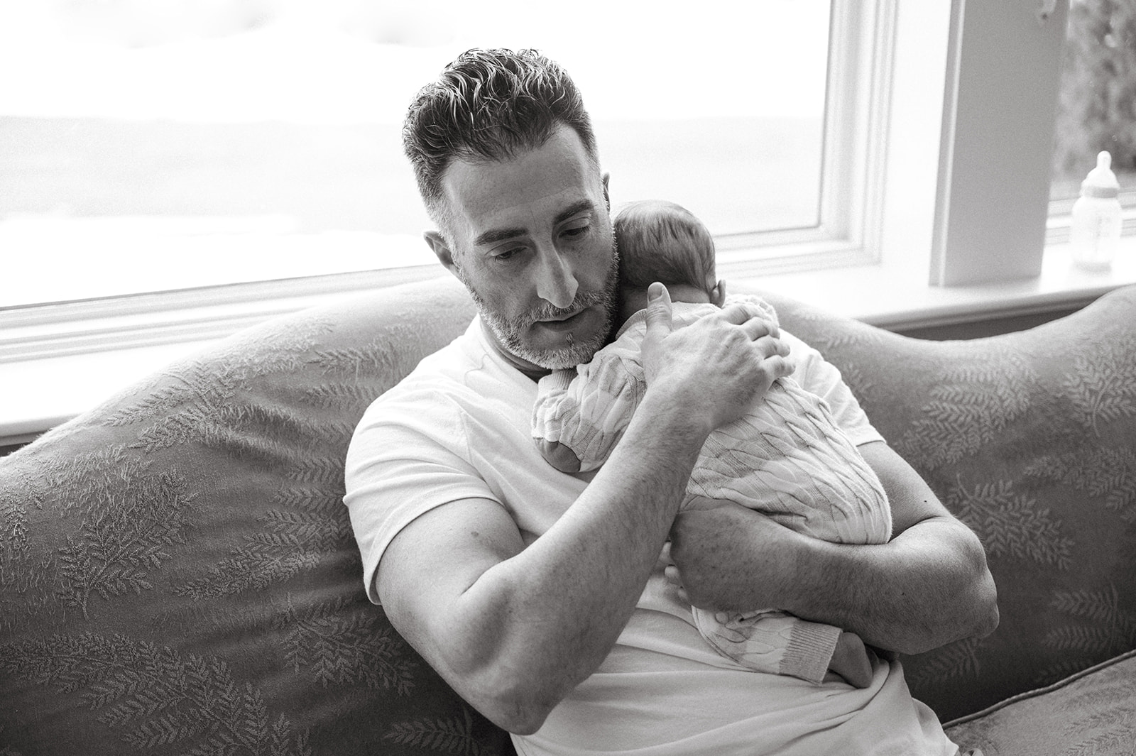 Black and white photo of dad holding his newborn baby 