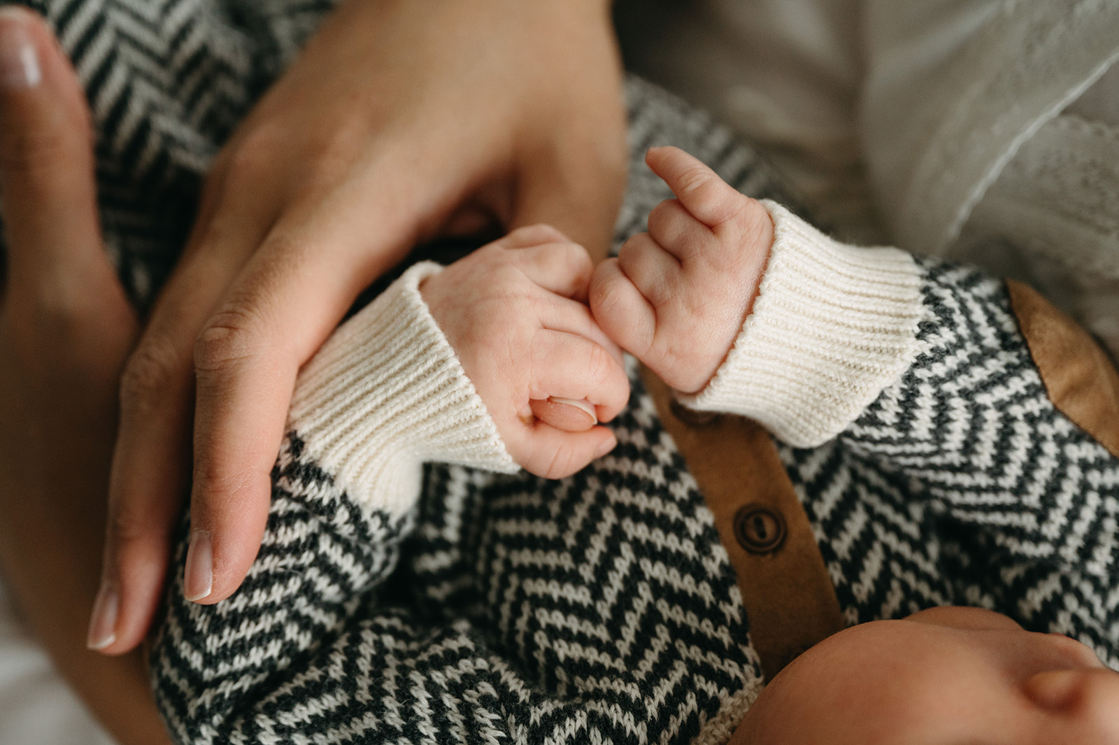 Loving parents holding their newborn's tiny hand in a close-up shot.