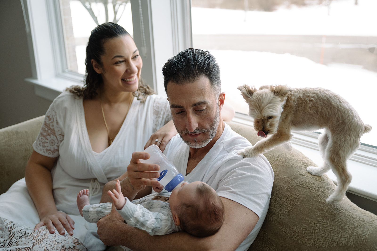 New Parents in Pittsburgh, PA snuggling new baby with family dog