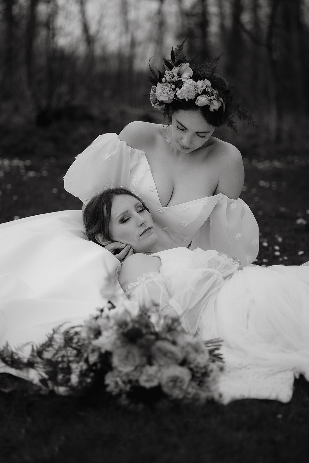 two brides sit and snuggle together on the grounds of Mapledurham House wedding venue in the spring sunshine