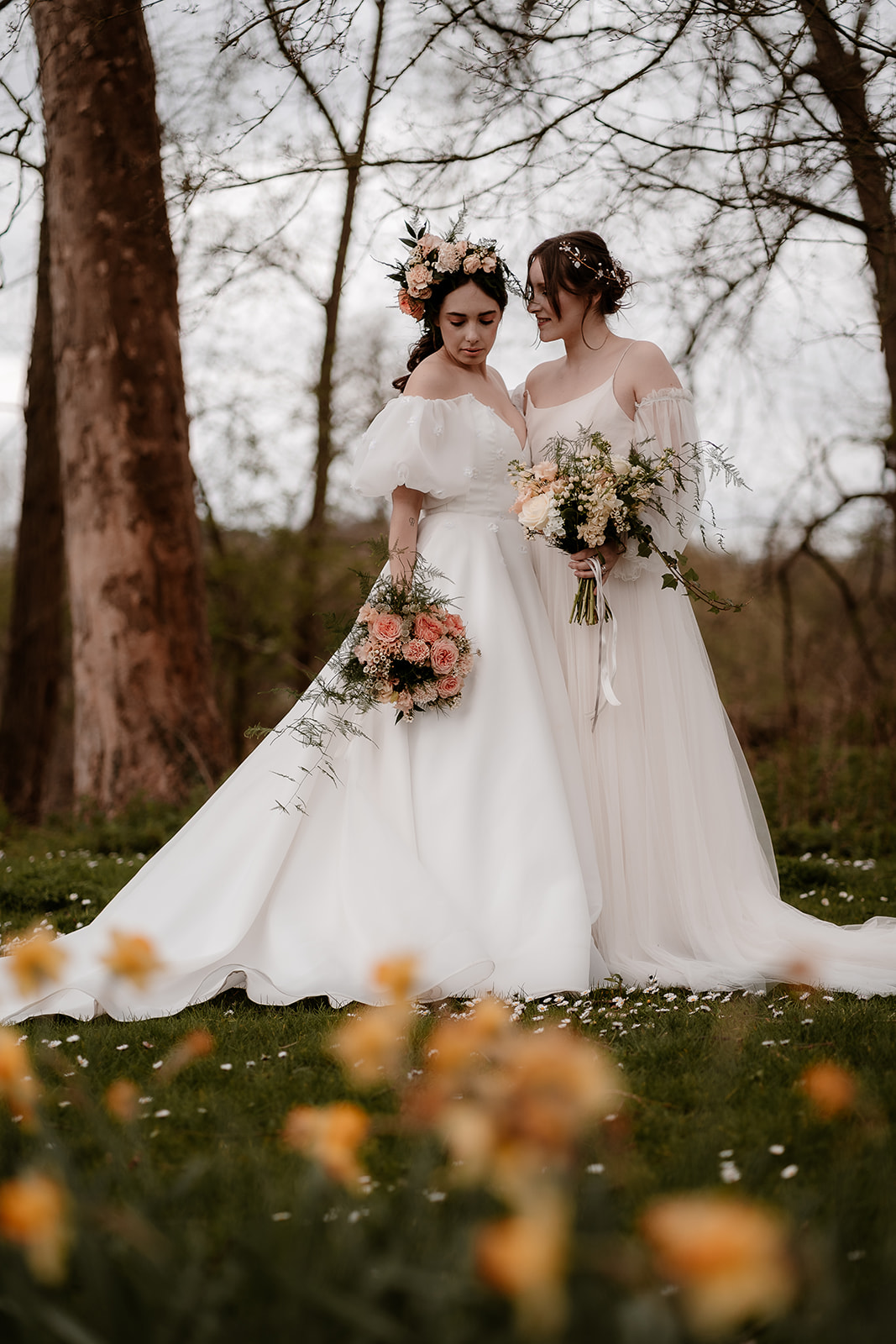 Two brides stand together among the daffodils at Mapledurham House wedding venue