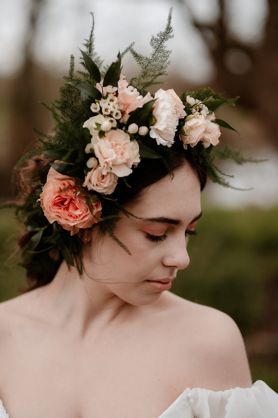 Head and shoulders shot of a bride wearing a large flower crown with peach flowers