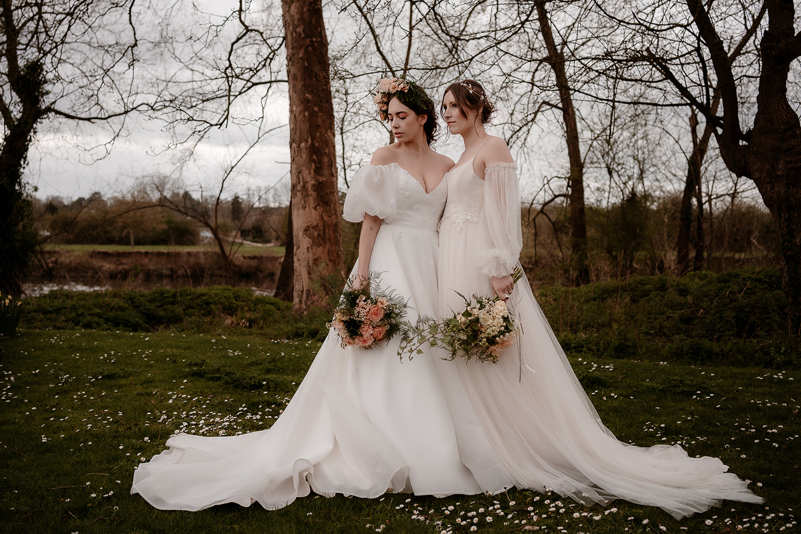 Two brides stand together among the daisies at Mapledurham House wedding venue