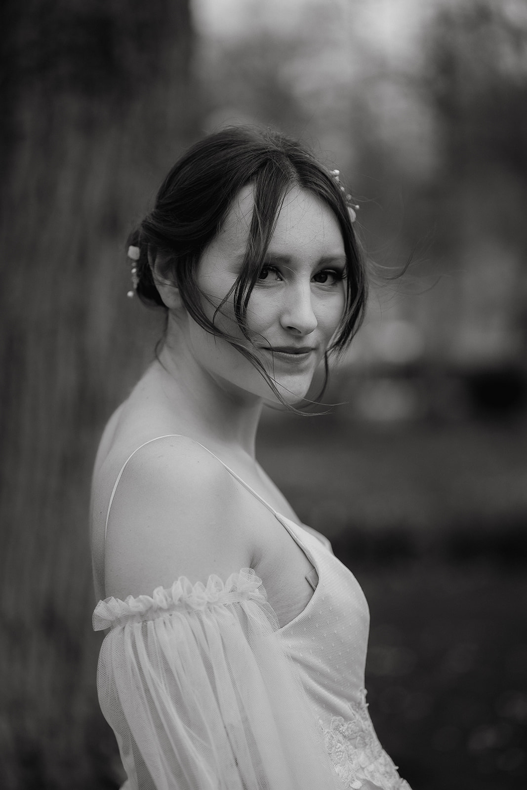 black and white photo of a Bride in a tulle wedding dress with sheer sleeves and soft, loose bun
