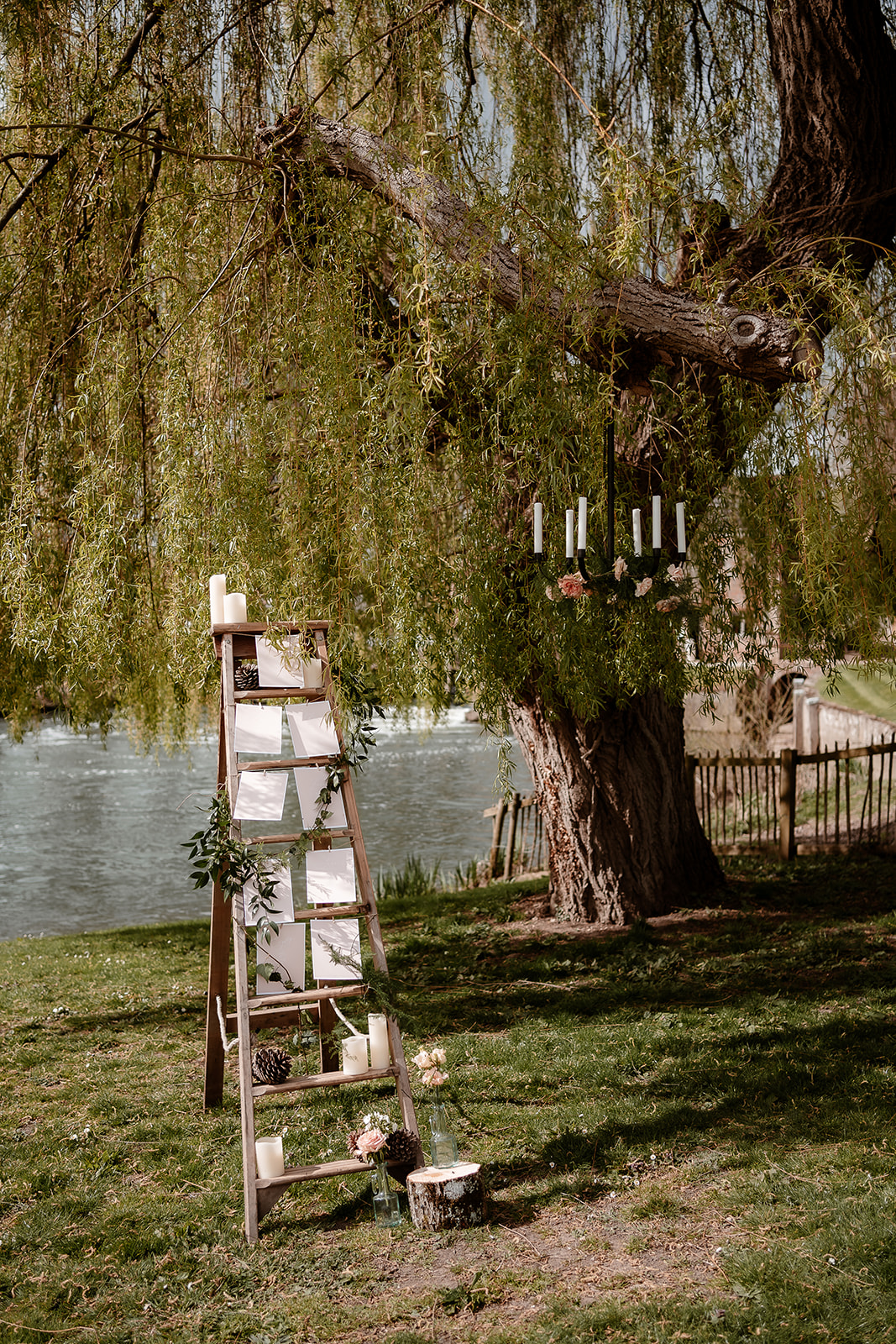 Rustic ladder seating plan by the willow tree at Mapledurham House with a flower chandelier hanging from the branches