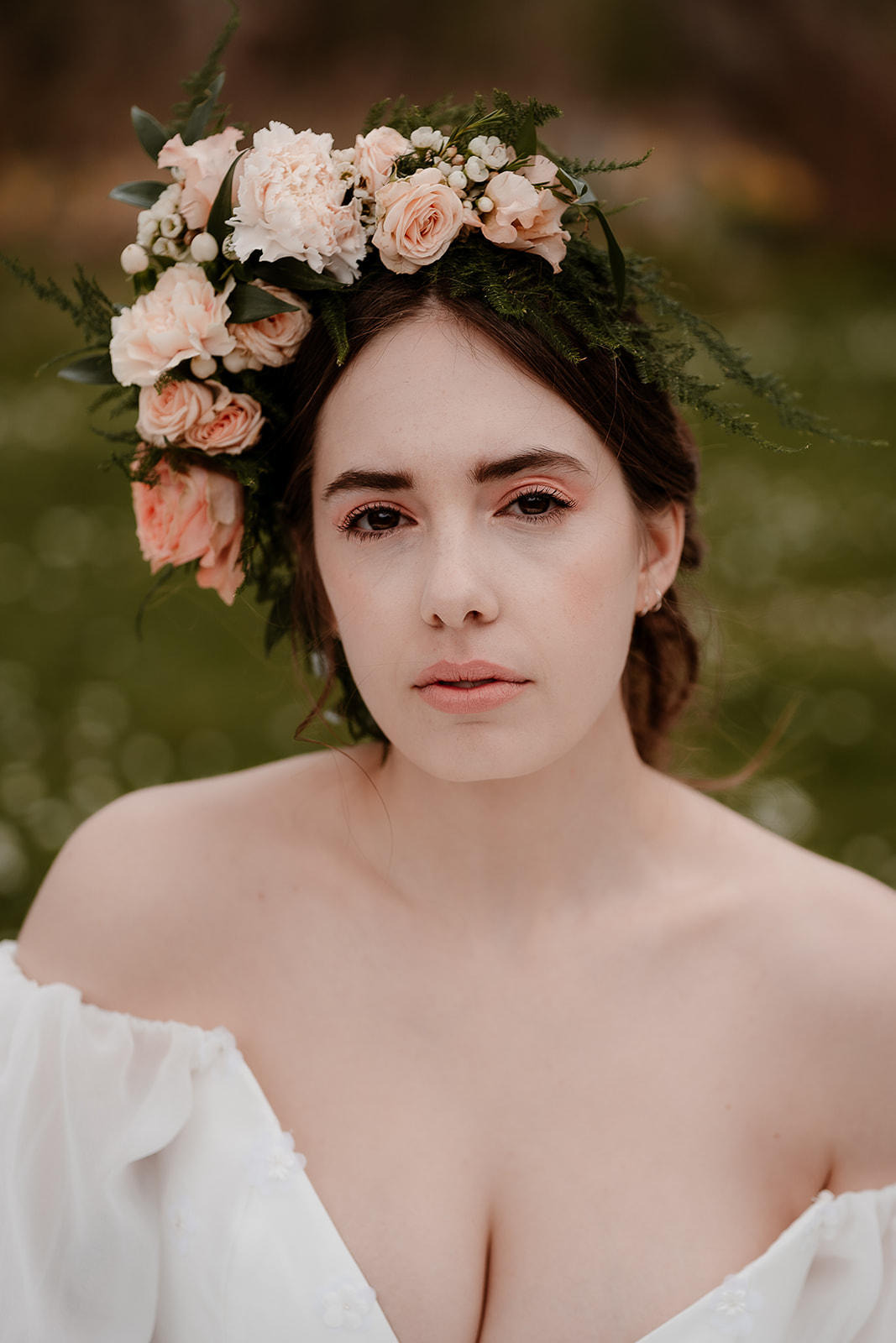portrait of a bride wearing a flower crown and off the shoulder wedding dress with puff sleeves