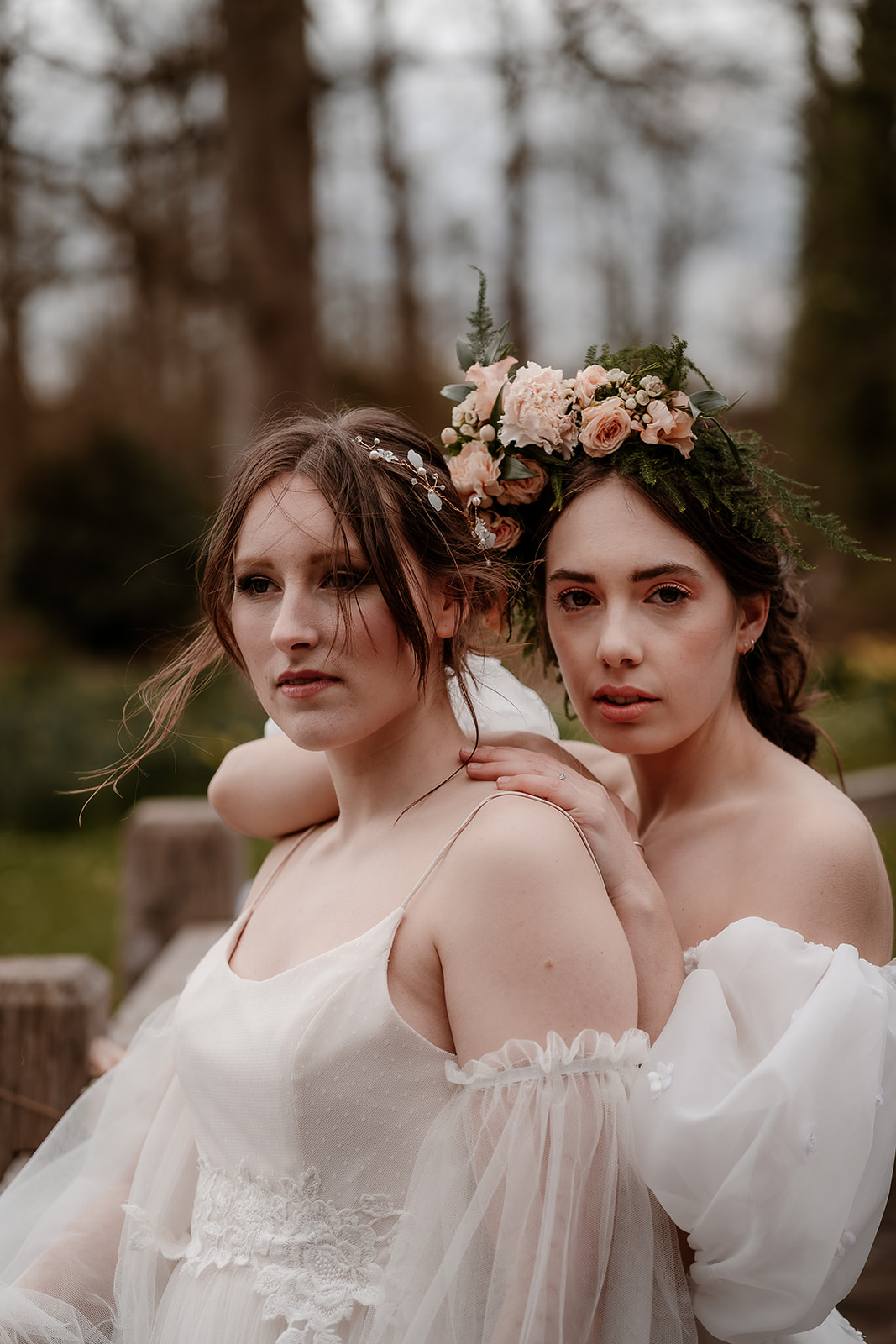 Two brides stand together on a bridge and stare down the camera at Mapledurham House wedding venue