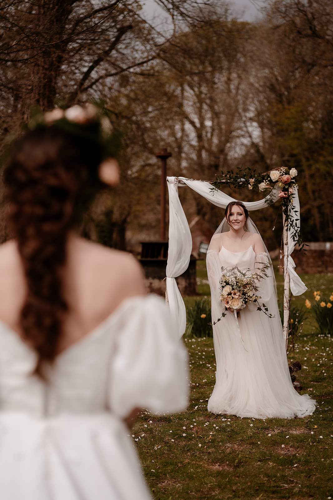 A bride walks towards her bride waiting for her at their outdoor ceremony arch at Mapledurham House