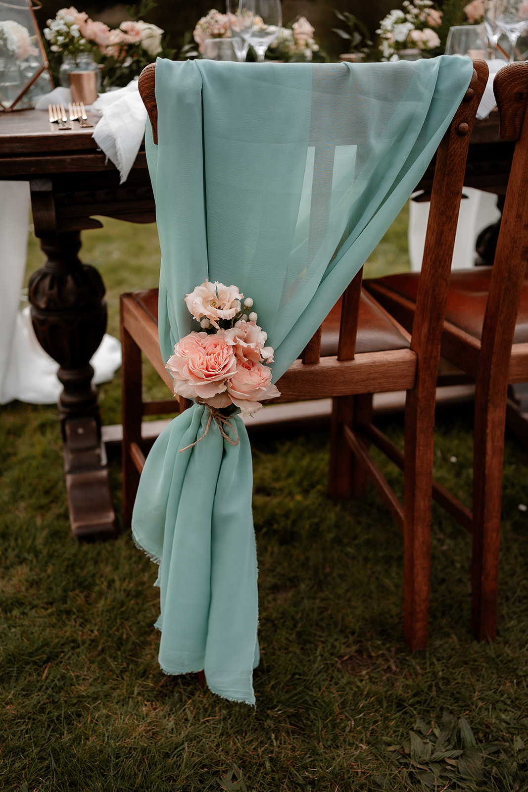 Soft green chiffon chair drapes with peach flower posy on the sweetheart table on the grounds of Mapledurham House