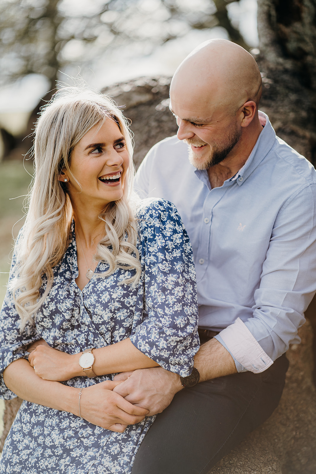 Couple laughing and having a great time together whilst snuggled in on their engagement shoot.