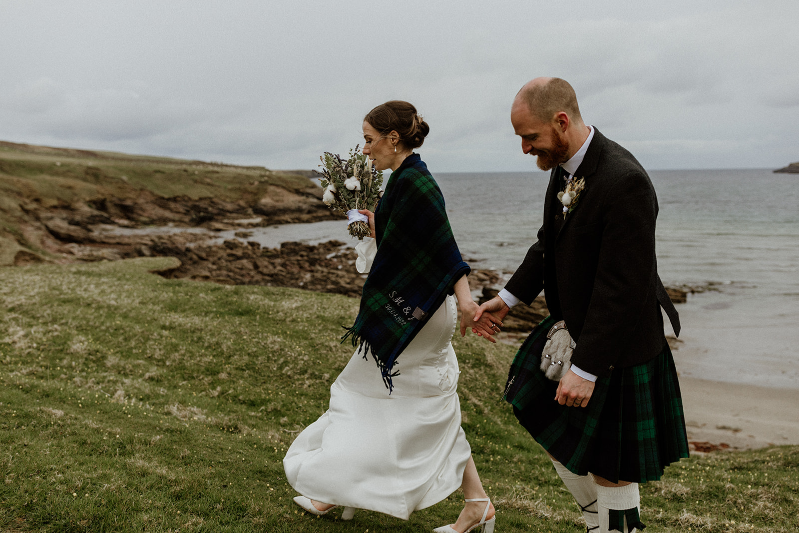 The bride wears a personalised blanket from The Tartan Blanket Co. as a wedding shawl in Shetland.