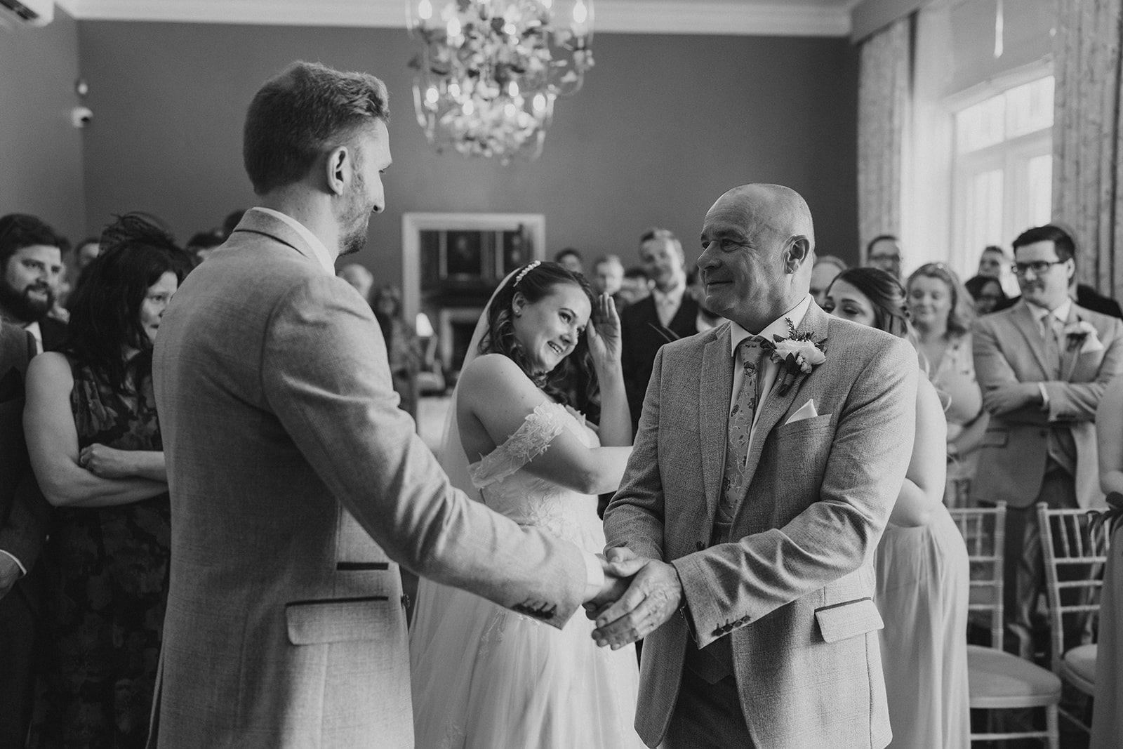 The groom and the father of the bride, shaking hands at the bottom of the wedding aisle