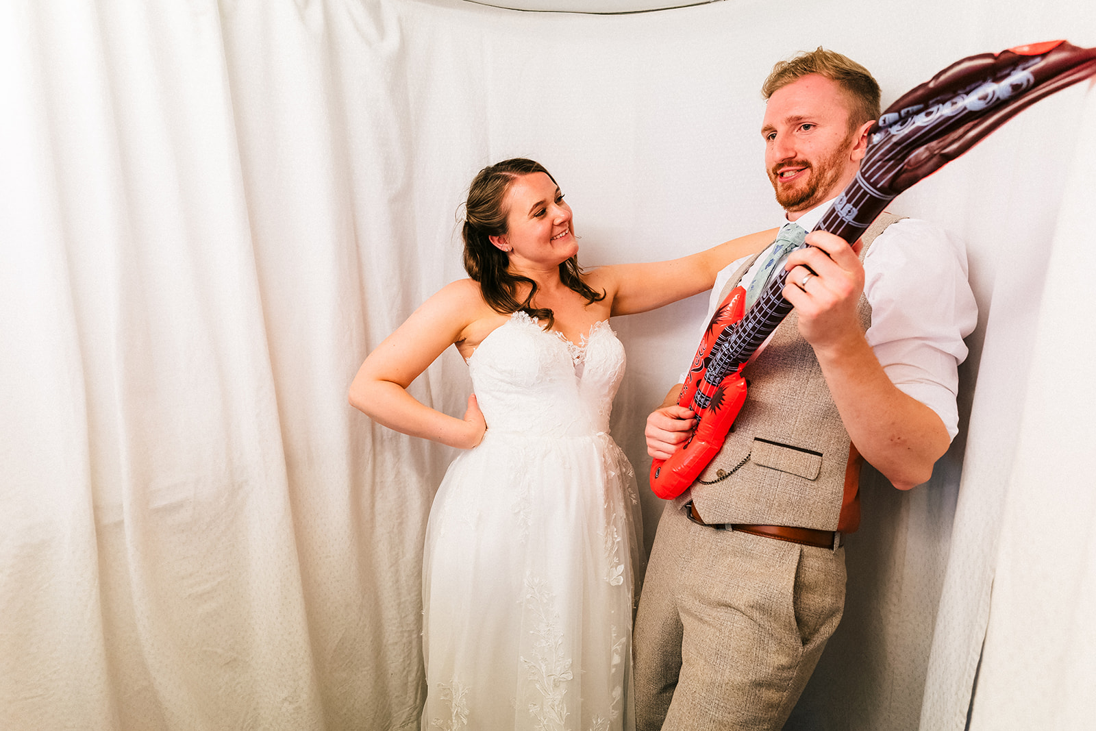 The bride and groom with an inflatable guitar in a photo booth